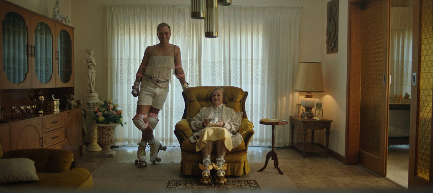 Episode #389: a skater in costume beside an older woman in an armchair