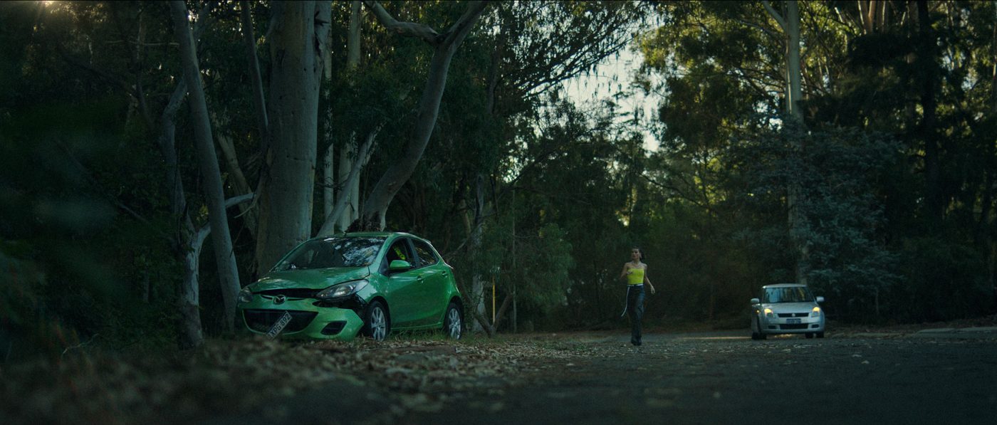 Episode #448: a woman walks down a tree-shaded road between two cars